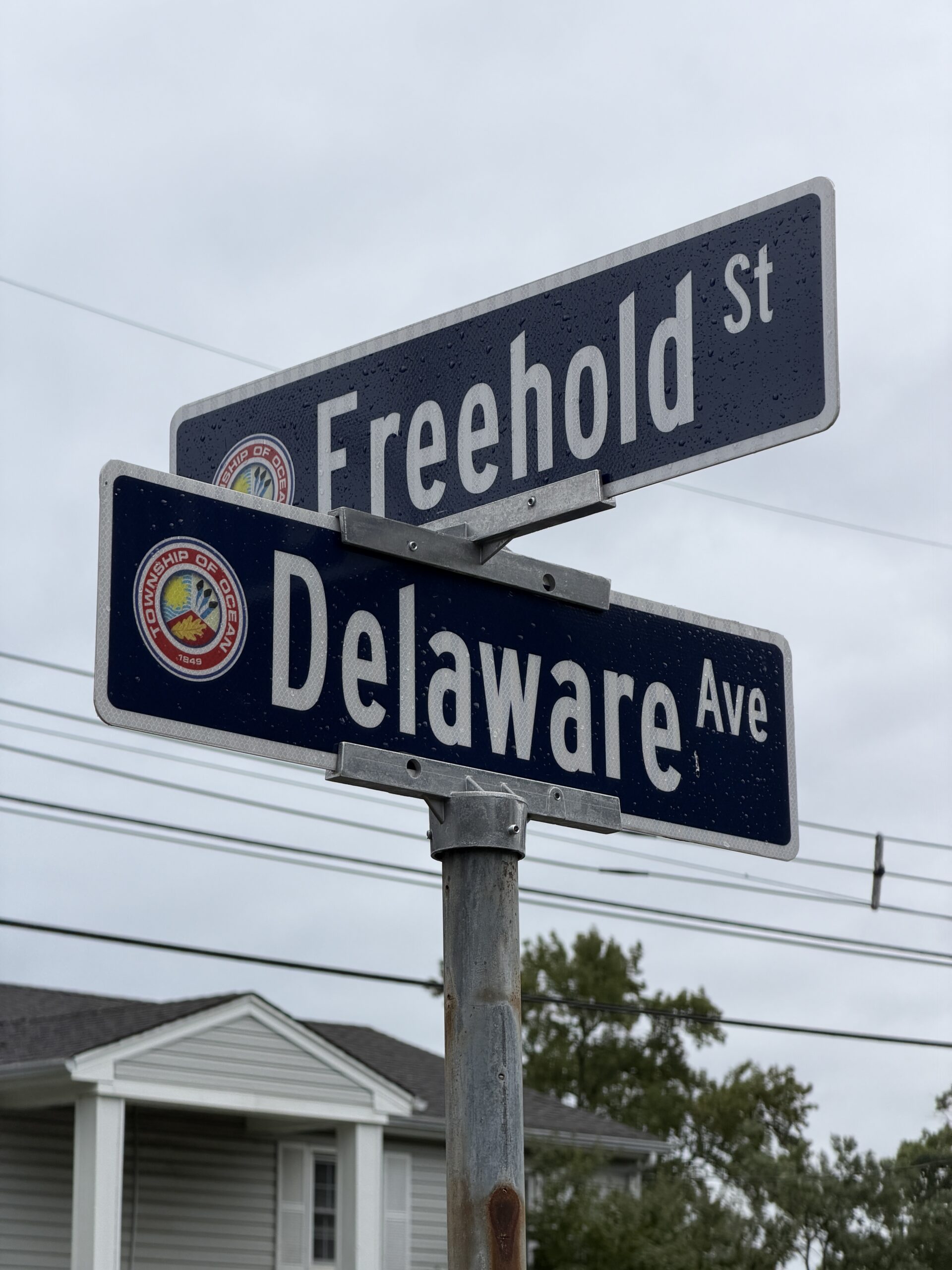 Street signs for Freehold Street and Delaware Avenue in Ocean Township NJ, featuring the township emblem.